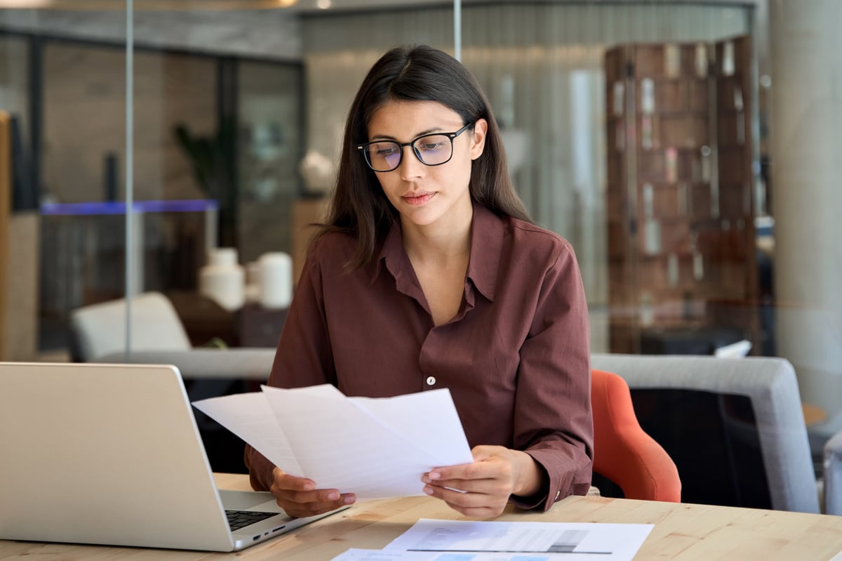 A focused businesswoman reviewing financial documents on a laptop in the office