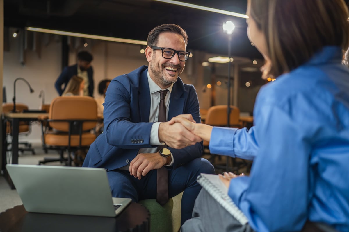 Business partners shaking hands in a modern office, symbolizing trust and partnership